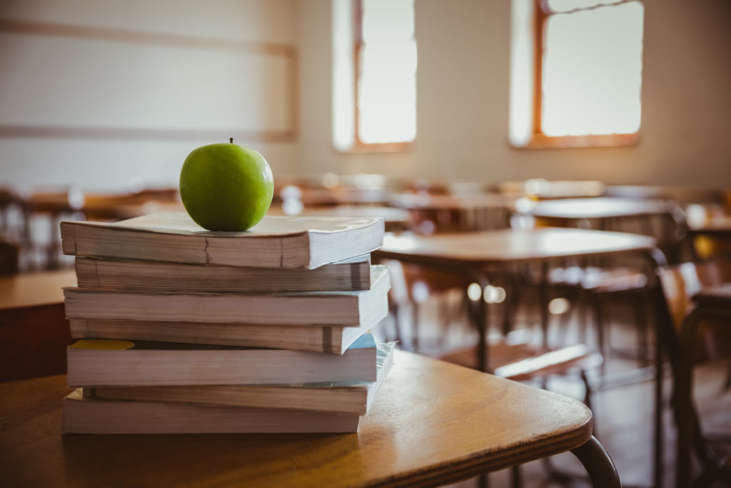 apple on stack of books ondesk in classroom